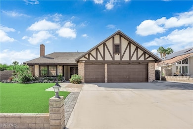 Tudor home with stucco siding, a front yard, concrete driveway, a chimney, and an attached garage