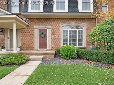Doorway to property featuring mansard roof, a shingled roof, brick siding, and a lawn