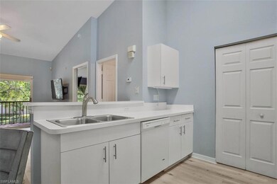 Kitchen featuring vaulted ceiling, kitchen peninsula, white cabinetry, white dishwasher, and sink