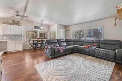 Living room with plenty of natural light, a ceiling fan, dark wood finished floors, and vaulted ceiling