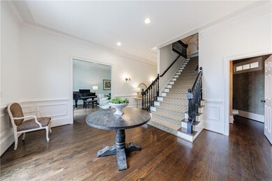 Entrance foyer with a decorative wall, crown molding, stairway, and wood finished floors