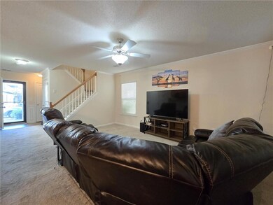 Living room featuring light carpet, crown molding, stairs, a textured ceiling, and a ceiling fan