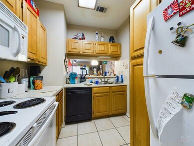 Kitchen featuring white appliances, light tile pa