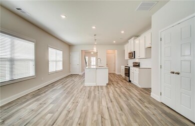 Kitchen featuring recessed lighting, pendant lighting, stainless steel appliances, white cabinets, and light wood-style flooring
