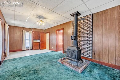 Unfurnished living room with visible vents, wood walls, a wood stove, and a paneled ceiling