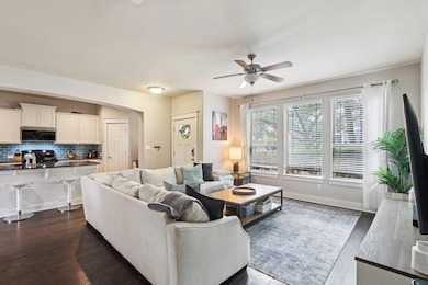 Living area featuring dark wood-style flooring, a ceiling fan, and arched walkways