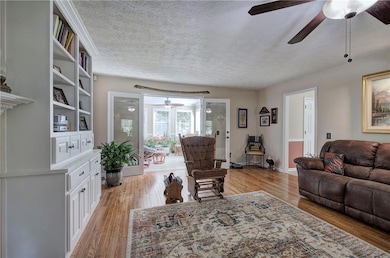 Living room featuring ceiling fan, a textured ceiling, and light wood-style floors