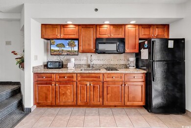 Kitchen with black appliances, light stone counter