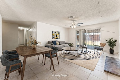Living room with light tile patterned floors, a textured ceiling, and a ceiling fan