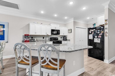 Kitchen with black appliances, baseboards, white cabinets, decorative backsplash, and a breakfast bar