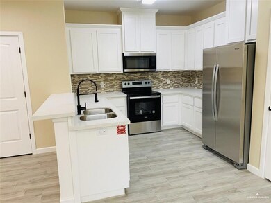 Kitchen with white cabinets, appliances with stainless steel finishes, a sink, light countertops, and backsplash