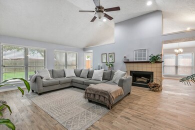 Large open family room with new wood like tile, fresh paint and gas log fireplace.