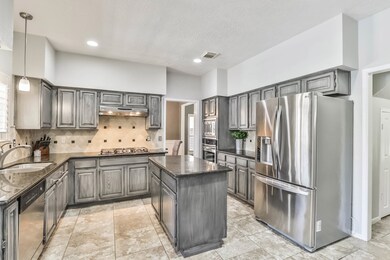 Gorgeous kitchen with gray cabinets, ample granite counters, stone backsplash, and stainless appliances. The perfect cook's kitchen!