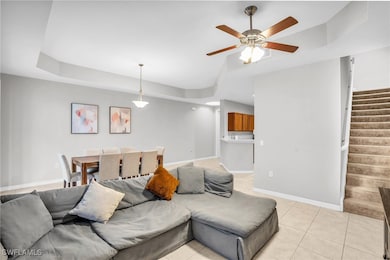 Tiled living room with ceiling fan and a tray ceil