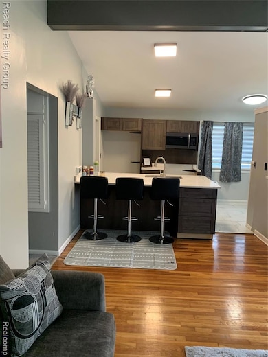 Kitchen with a breakfast bar area, light countertops, light wood-style flooring, fridge, and a peninsula