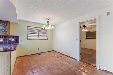 Unfurnished dining area featuring a textured ceiling, a chandelier, ceiling fan, and light tile patterned flooring