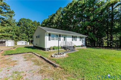 View of front of home featuring a front yard, crawl space, an outbuilding, view of wooded area, and a shingled roof