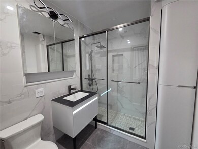 Bathroom featuring vanity, tile walls, a marble finish shower, and tile patterned flooring