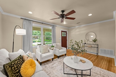 Living room featuring a ceiling fan, crown moldin