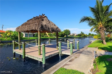 View of dock with a gazebo, a lawn, and a water view