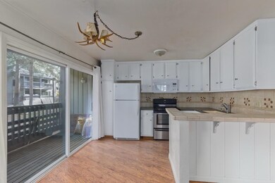 Kitchen with tile counters, white appliances, tasteful backsplash, white cabinets, and light wood-type flooring