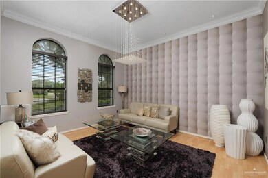 Living room with hardwood / wood-style flooring, crown molding, and a chandelier