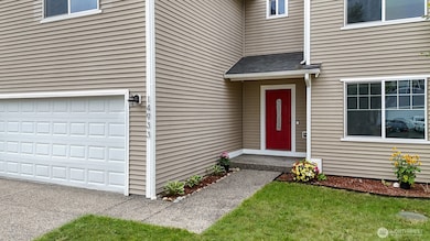 Pathway leads to covered front entry with red door. Grass has been digitally edited for photos.
