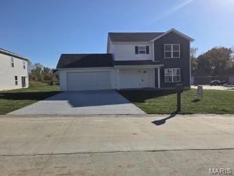 Traditional-style home with a front yard, concrete driveway, covered porch, and an attached garage