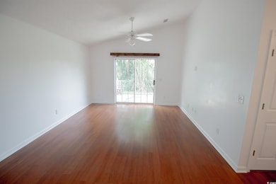 Empty room featuring ceiling fan, lofted ceiling, wood finished floors, and baseboards