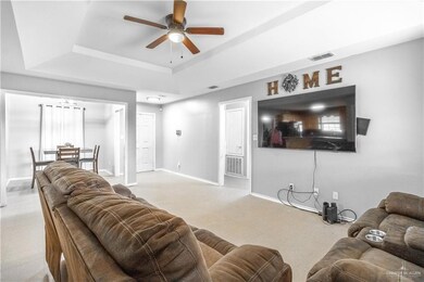 Living room with ceiling fan and a raised ceiling