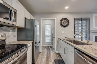Kitchen featuring white cabinets, light stone coun