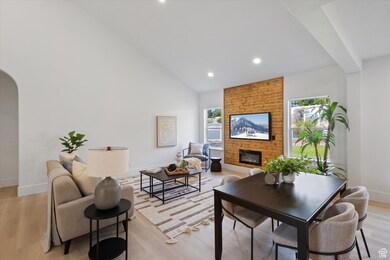 Living area featuring light wood-style floors, a fireplace, arched walkways, high vaulted ceiling, and recessed lighting