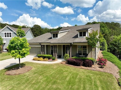 Traditional-style house featuring covered porch, a front yard, roof with shingles, concrete driveway, and an attached garage