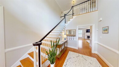 Spacious foyer with soaring ceilings, crown molding, and hardwood flooring. Abundant natural light enhances the elegant architectural details.