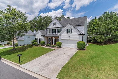 Traditional-style house featuring a front lawn, driveway, a shingled roof, and a garage
