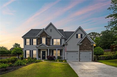 View of front of house featuring stone siding, an attached garage, driveway, and a yard