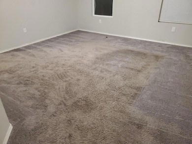 Carpeted spare room featuring baseboards