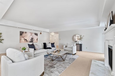 Living area featuring light colored carpet, a fireplace, and crown molding
