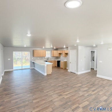 Kitchen featuring open floor plan, a peninsula, light countertops, light brown cabinetry, and light wood-style floors