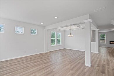 Unfurnished living room with a chandelier, healthy amount of natural light, recessed lighting, light wood-style floors, and baseboards
