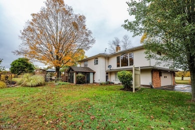 Back of house featuring a yard, a chimney, an attached garage, and brick siding