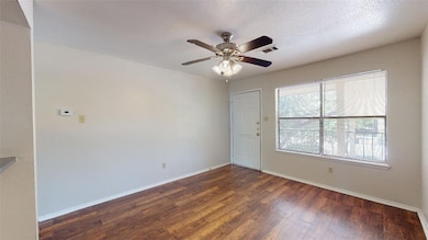Empty room with dark wood-style flooring, a ceiling fan, and a textured ceiling
