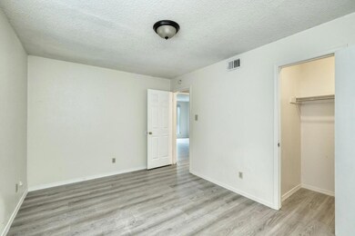 Unfurnished bedroom with a textured ceiling, light wood-type flooring, and a walk in closet