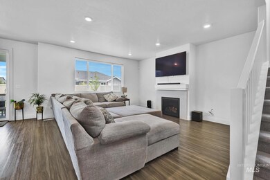 Living room featuring stairway, dark wood-style floors, a lit fireplace, and recessed lighting