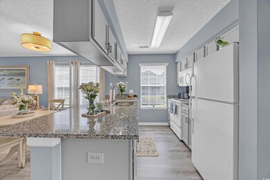 Kitchen with white appliances, a textured ceiling, a sink, a peninsula, and light wood-type flooring
