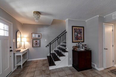 Foyer entrance with a textured ceiling, ornamental molding, and tile patterned floors