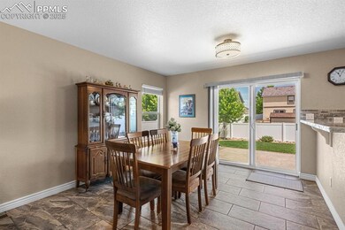 Dining room featuring baseboards, a textured ceiling, and a textured wall