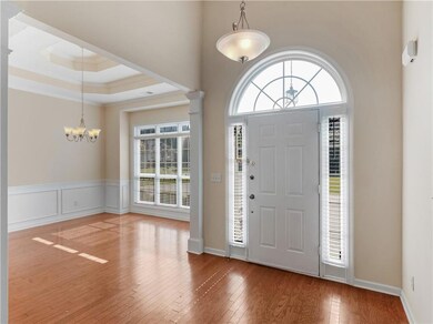 Foyer entrance with a chandelier, healthy amount of natural light, hardwood / wood-style flooring, ornate columns, and crown molding