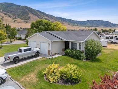 Ranch-style home with a garage, a mountain view, a front lawn, and concrete driveway