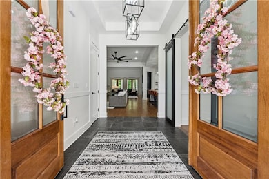 Entryway featuring a barn door, a tray ceiling, and a ceiling fan